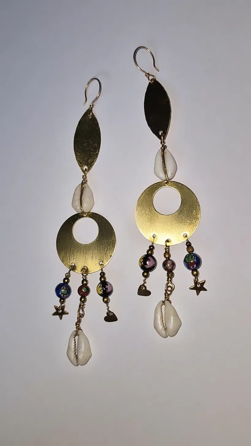 Brass leaf, cowrie and cloisonné earrings in warm light